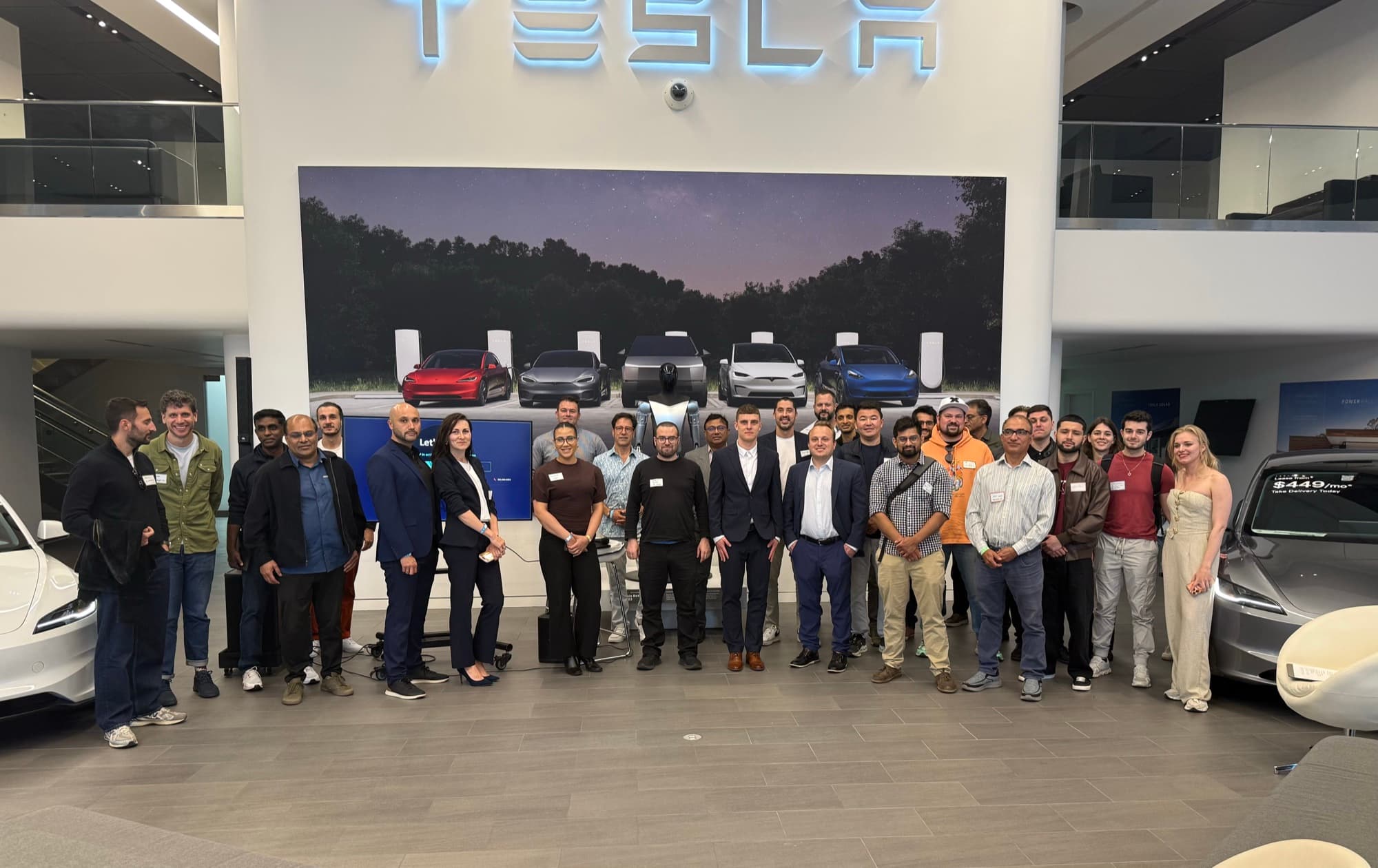 The full room at a Startup Valley San Francisco pitch night, group photo under the Tesla sign